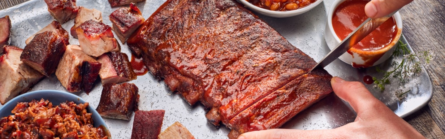 person cutting into some ribs, showcasing the gift of KC tour taste plate